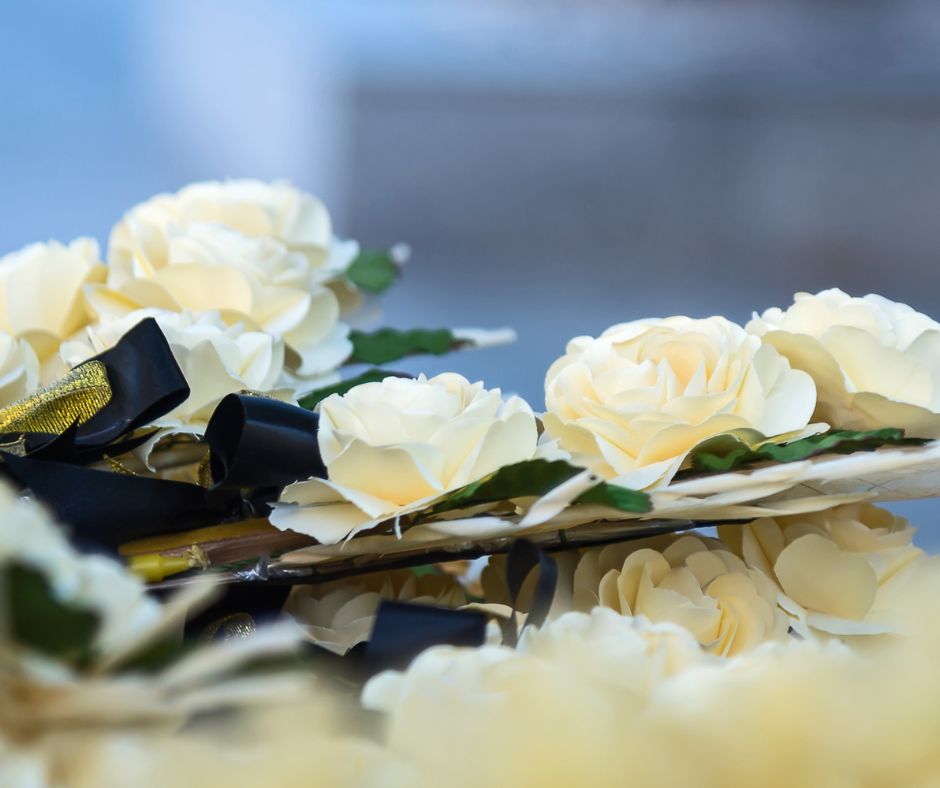 Un hermoso arreglo floral de rosas blancas sobre un ataúd que homenajea a una persona que contaba con un Seguro de Servicios Funerarios