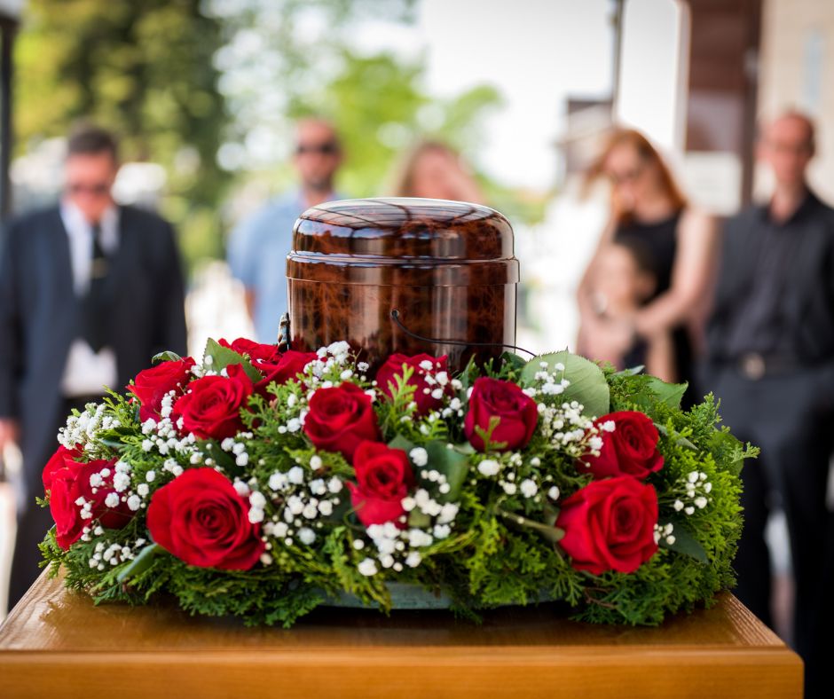 Urna con un hermoso arreglo floral y familiares homenajeando a su familiar con la tranquilidad de contar con un Seguro de Servicios Funerarios